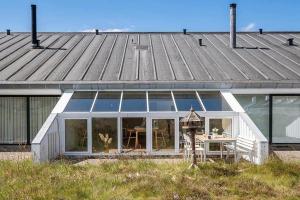 a house with glass doors and a table in front of it at BL1001-Blokhus-Ferren-95 in Blokhus