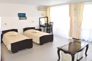 a hotel room with two beds and a coffee table at Hotel Klisura in Sunny Beach