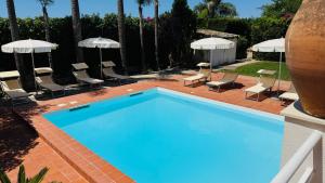 a large blue swimming pool with chairs and umbrellas at Villa Bruno in Modica