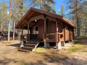 a small log cabin in the woods with a porch at Kolmiloukon leirintämökit in Taivalkoski