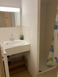 a white bathroom with a sink and a mirror at Pool and beach studio in Quiberon