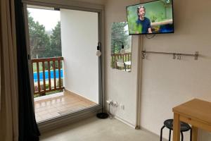 a room with a door to a balcony with a television at Pool and beach studio in Quiberon