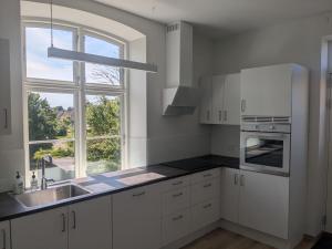 a white kitchen with a sink and a window at Stubbekøbing City View Stopover in Stubbekøbing