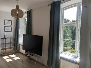 a living room with a flat screen tv and two windows at Stubbekøbing City View Stopover in Stubbekøbing