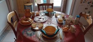 a dining room table with a red table cloth with dishes and cups at Chambre très calme in Montélimar