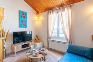 a living room with a blue couch and a tv at Le Refuge des Embruns - Port & plages - 4 pers - Tout confort et équipé in LʼHerbaudière