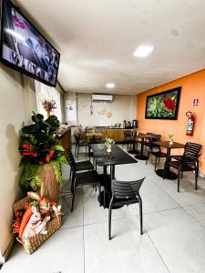 a dining room with tables and chairs and a tv at Hotel Caeté in Bragança