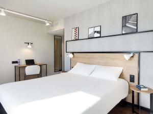 a bedroom with a large white bed and a desk at Ibis Clermont-Ferrand Centre Stade in Clermont-Ferrand +276 photos
