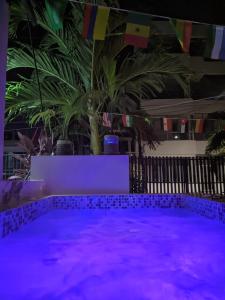 a pool with purple lights in a room with palm trees at El coltejeriano in Coveñas