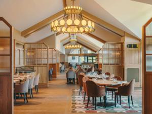 a restaurant with tables and chairs and a chandelier at Fairmont Cheshire The Mere in Knutsford