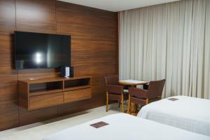 a hotel room with a television and a table with chairs at Hotel Gran Odara in Cuiabá