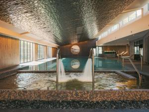 a swimming pool with a waterfall in a building at Fairmont Cheshire The Mere in Knutsford