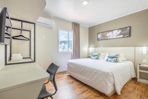 a bedroom with a bed and a desk and a window at Hotel Bella Camboriú in Balneário Camboriú