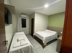 a hotel room with two beds and a television at Hotel Caeté in Bragança