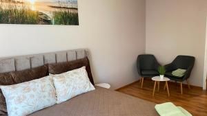 a bedroom with a bed and a black chair at Pie dzintara jūras in Apšuciems