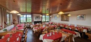 a restaurant with tables and chairs with red tablecloths at Berggasthof Hinhart in Regen