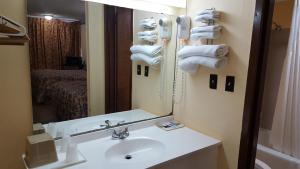 a bathroom with a sink and a mirror and towels at Innkeeper Motel Hamel in Hamel