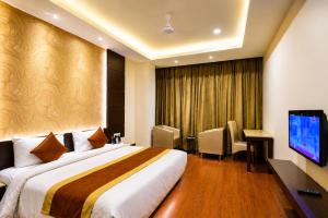 a hotel room with a bed and a flat screen tv at Hotel Paarth in Ludhiana