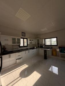 a large kitchen with white cabinets and a table at Al Rabi Rest House in Khor Fakkan