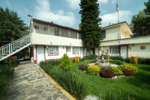 a building with a garden in front of it at Capital O Hotel Meson Del Rio, Tepotzotlan in Tepotzotlán