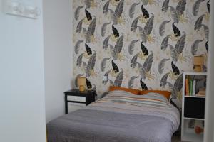 a bedroom with a bed with a wallpaper with birds on it at Gîte les Grands Orangers in Melle