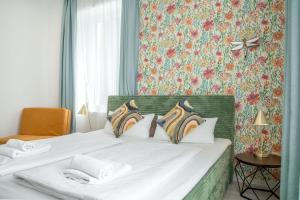 a bedroom with two white beds with floral wallpaper at Villa Vaicun - Boutique Rooms in Lörrach