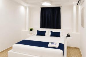 a bedroom with a large white bed with blue pillows at Hotel Urak in Valledupar