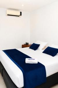 a bedroom with a large white bed with blue pillows at Hotel Urak in Valledupar