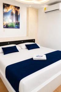 a bedroom with a large white bed with blue pillows at Hotel Urak in Valledupar
