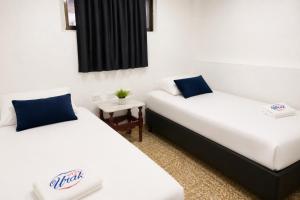 a room with two beds with blue pillows at Hotel Urak in Valledupar