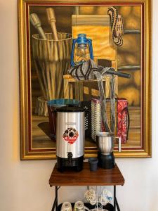 a coffee maker on a table in front of a painting at Hotel Urak in Valledupar