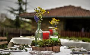 a table with a glass vase with flowers in it at къща Утринна Роса in Blŭskovtsi