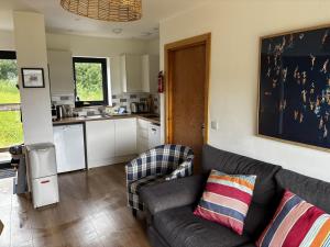 a living room with a couch and a kitchen at Achnacolain Lodge in Tarbert