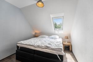a bedroom with a bed and a window at Haus Am Dorfteich B eingefriedet in Fehmarn