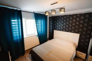 a bedroom with a bed with blue curtains and a window at Danube Breeze Apartment in Giurgiu