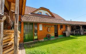 a wooden house with green doors and a grass yard at Apartment Ursa Major & Glamp Barba in Preddvor