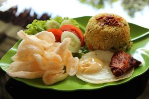 un plato verde de comida con arroz y verduras en Venezia Homestay and Garden en Yogyakarta