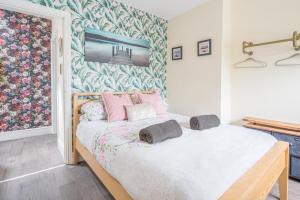 a bedroom with a bed with pink pillows on it at Charming Cottage, Lake District in Little Broughton