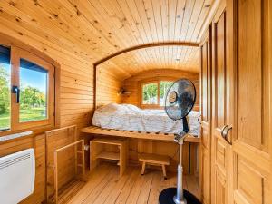 a small room with a bed and a fan at Blue : La Roulotte du Médoc in Naujac-sur-Mer