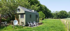a small green house with chairs in a field at Tiny House Climatisée Bernières in Bernières