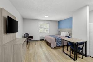 a hotel room with a bed and a desk and a tv at Suburban Studios Copley Akron West in Copley +8 photos