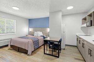 a hotel room with a bed and a table and a kitchen at Suburban Studios Copley Akron West in Copley