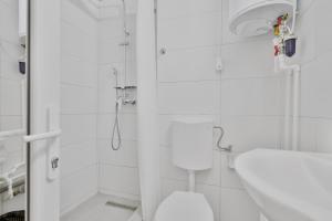 a white bathroom with a toilet and a shower at Neptune Breeze in Neptun