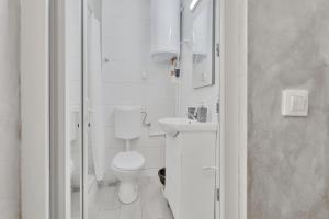 a white bathroom with a toilet and a sink at Neptune Breeze in Neptun