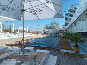 a swimming pool with an umbrella and some people in the water at Lotus 7 Silver in Mamaia