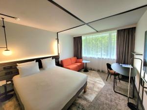 a hotel room with a bed and a chair at Novotel Lille Aéroport in Lesquin
