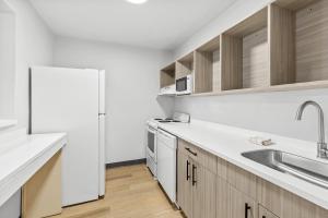 a white kitchen with a sink and a refrigerator at Suburban Studios Copley Akron West in Copley