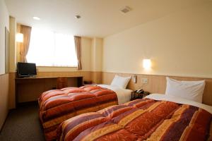 a hotel room with two beds and a television at New Grande Mimatsu in Takamatsu