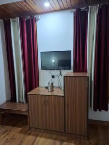 pokój z telewizorem z płaskim ekranem i zasłonami w obiekcie Hotel Moon In w mieście Kullu