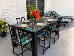 a black table with chairs and a vase of flowers at Les Hirondelles in Ngaparou